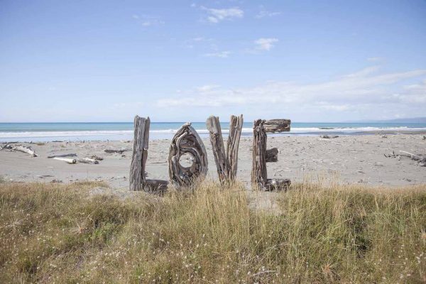 Artistic colour photo print of a human-sized Love sign made of driftwood sitting on Opotiki Beach, New Zealand.