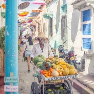Artistic colour photo print of a fruit seller pushing a cart loaded with fresh tropical fruit in Cartagena, Colombia.